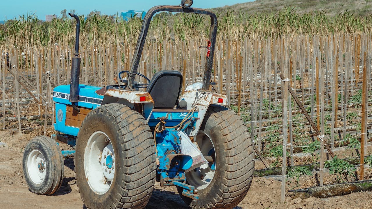 Distribución maquinaria agrícola Almería. A blue tractor parked in an agricultural field during daytime. Ideal for rural and agricultural themes.